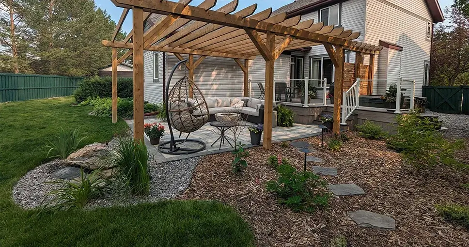 Cedar pergola over a patio with a hanging chair, sectional sofa, and fire pit in a backyard garden.