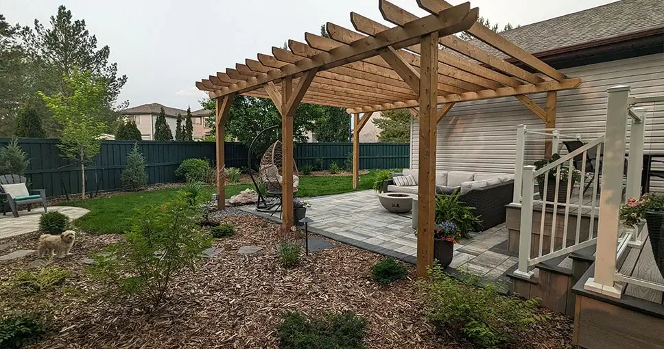 Wooden pergola over patio with furniture and dog.