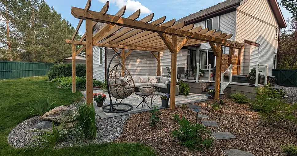 Cedar pergola over patio with hanging chair.