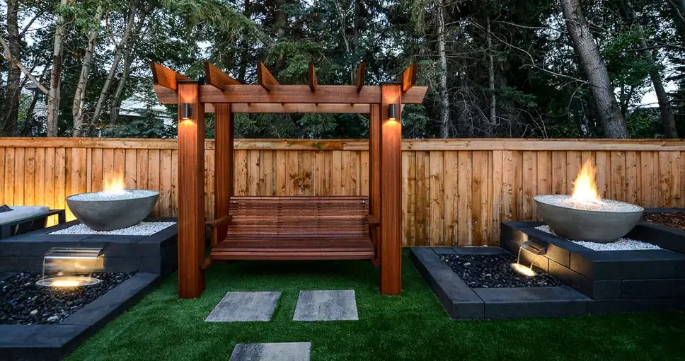 Modern backyard with a wooden pergola swing, fire bowls, and water features.
