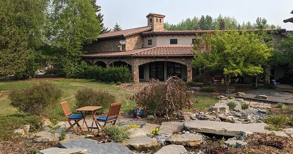 Rustic Mediterranean-style home with a landscaped garden and stone water feature.