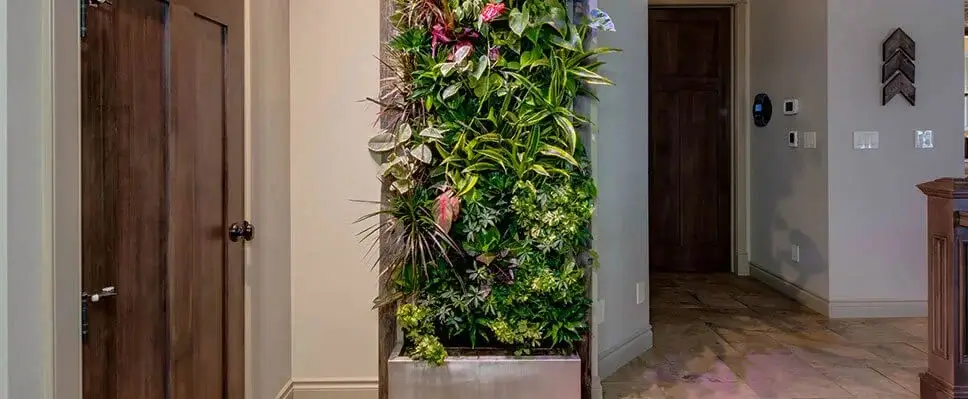 Indoor vertical garden Edmonton hallway with dense green plants, stone planter, wooden doors, and tiled flooring.