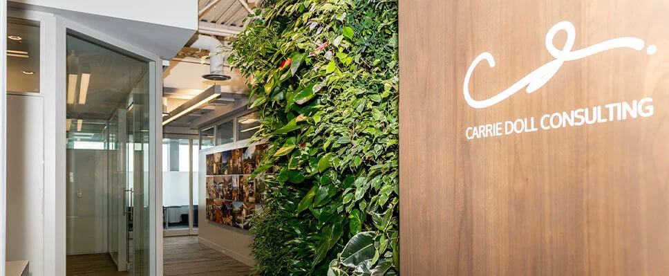 Office corridor in Edmonton with vertical green wall, wood paneling, and glass-walled rooms.