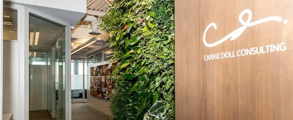 Office corridor in Edmonton with vertical green wall, wood paneling, and glass-walled rooms.