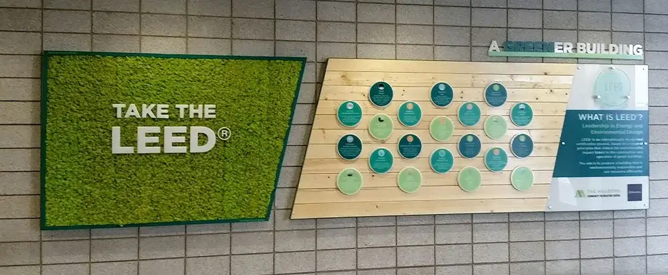 LEED promotional display with moss wall and informational panels on a tiled wall.