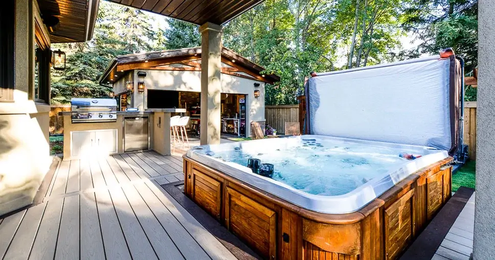 Outdoor deck with a hot tub and kitchen area.