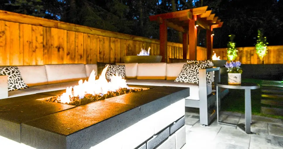 Cozy outdoor lounge with a modern fire pit, plush seating, and warm ambient lighting.