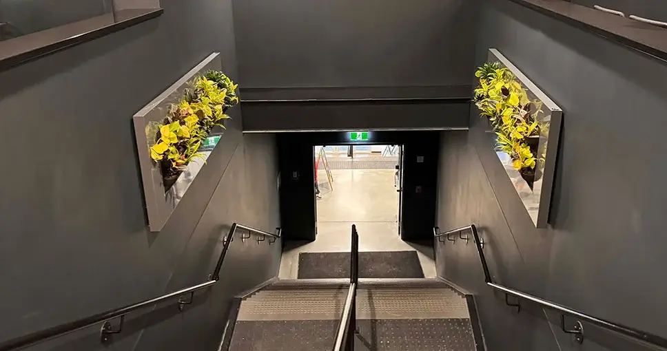 Staircase with vertical wall planters on dark walls.