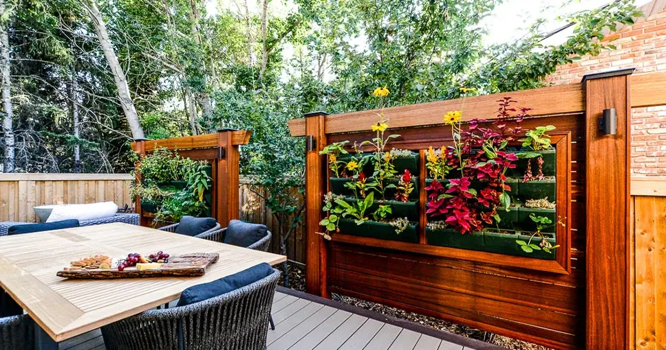 A custom wooden privacy screen featuring a built-in vertical garden with vibrant flowers and plants on a modern deck.