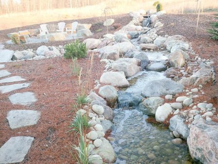 landscaped backyard with a prominent water feature, specifically a man-made stream and waterfall system.
