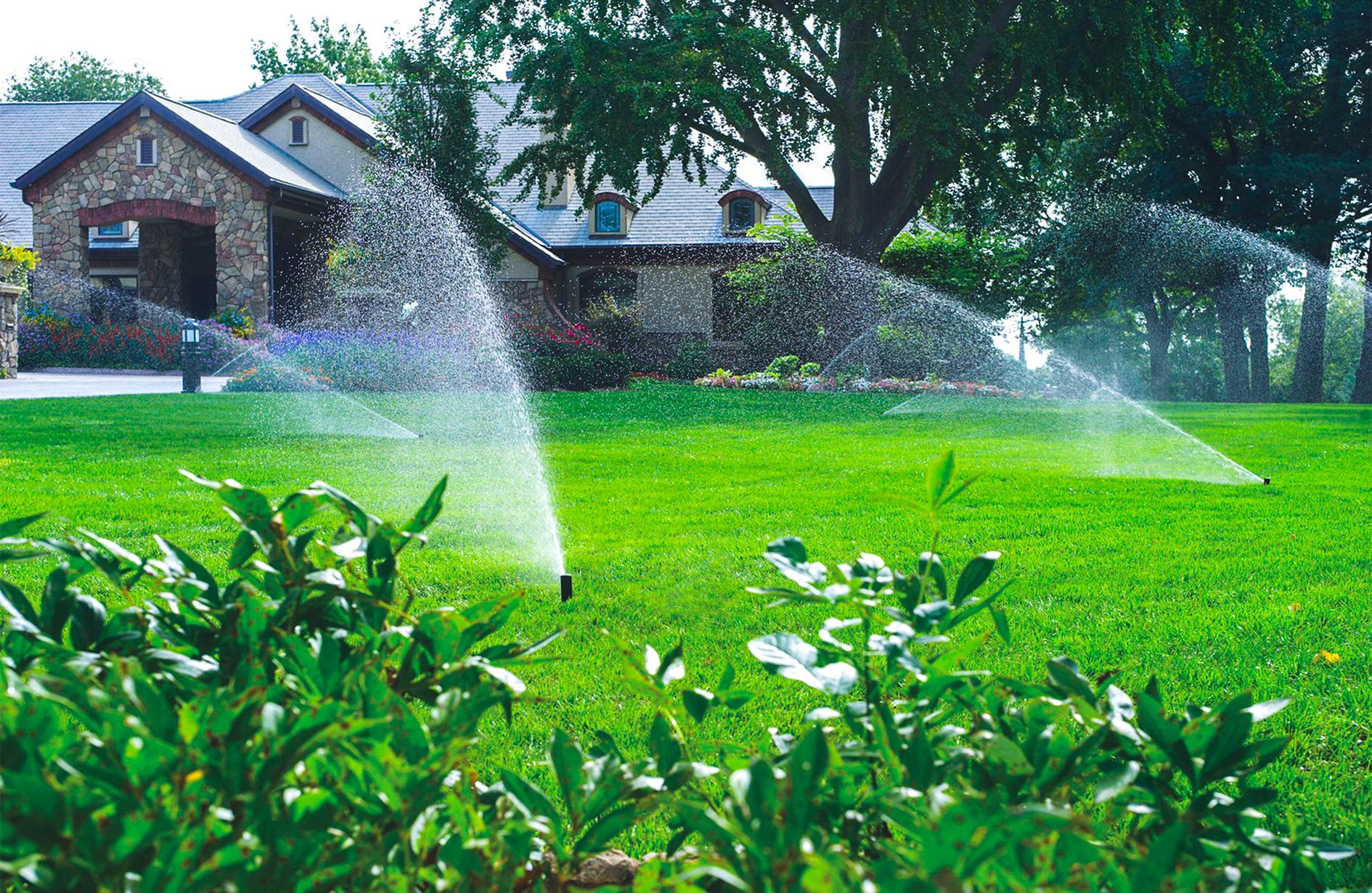 Irrigation systems in Edmonton with sprinklers watering a lush lawn and house.
