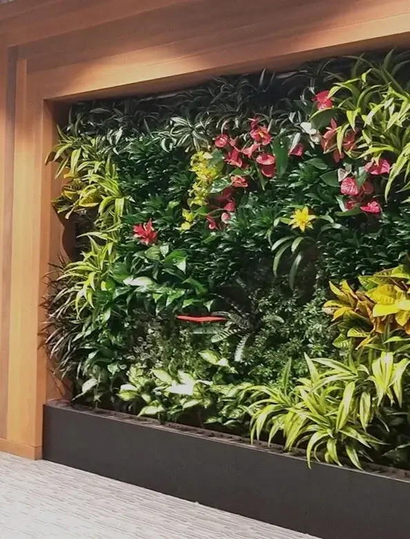 Indoor living wall with colorful flowers and green foliage showcasing biophilic landscaping and interior design in Edmonton.