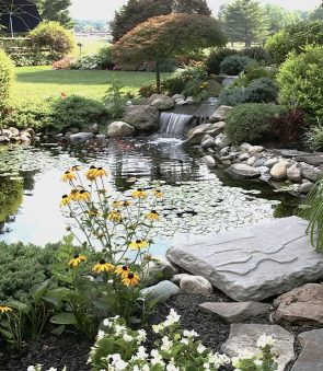 backyard pond with waterfall and lush garden by Landscaping in Edmonton