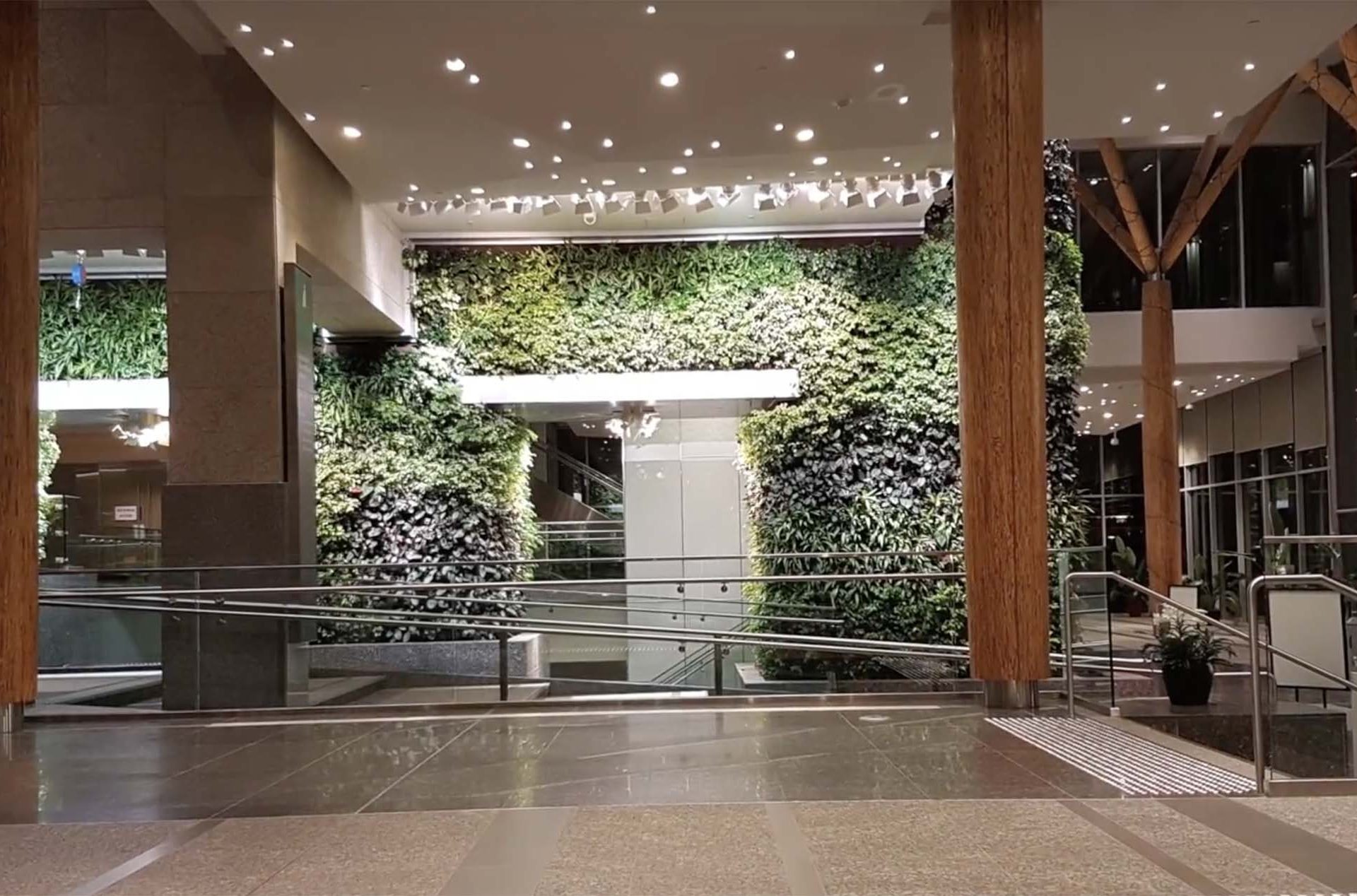 Indoor lobby with living walls, wooden columns, and polished floors.