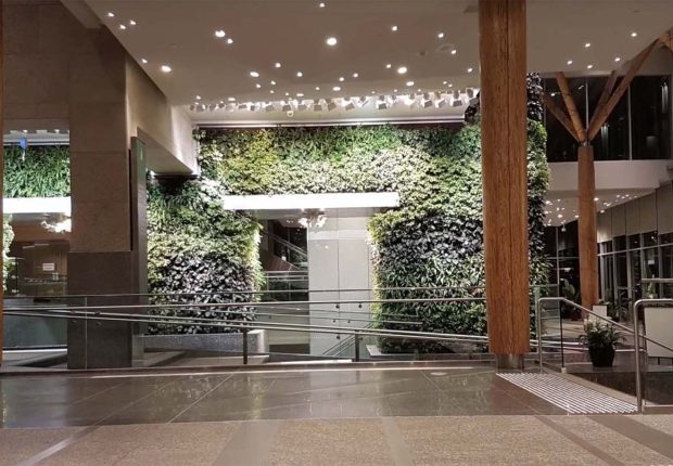 Indoor lobby with living walls, wooden columns, and polished floors.