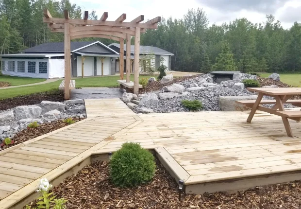 Large wooden deck with a timber pergola and rock waterfall.