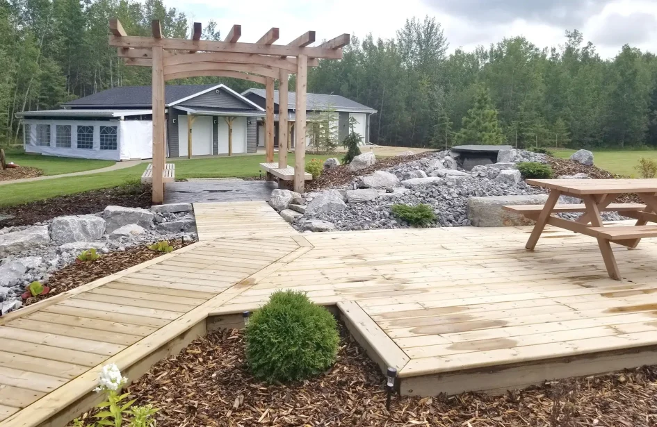 Large wooden deck with a timber pergola and rock waterfall.