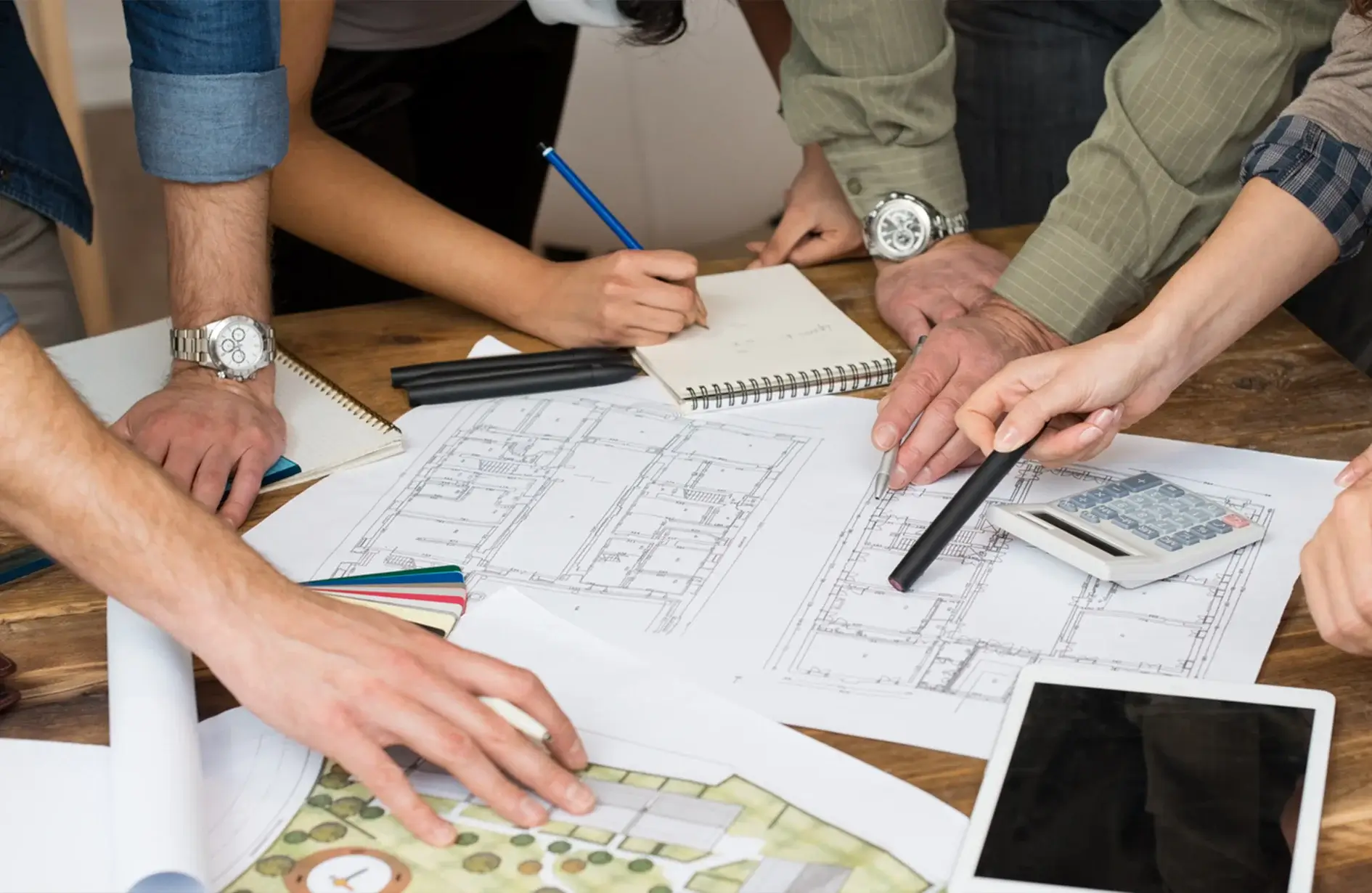 Team collaborating on luxury landscape design blueprints and plans on a table.