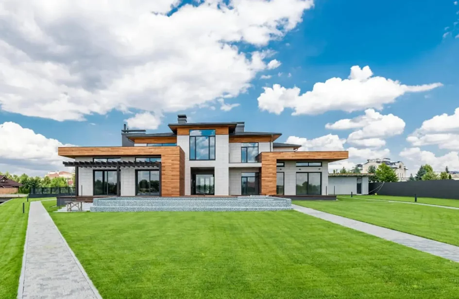 Contemporary house with wooden cladding, large glass windows, manicured green lawn, & paver paths in Edmonton.
