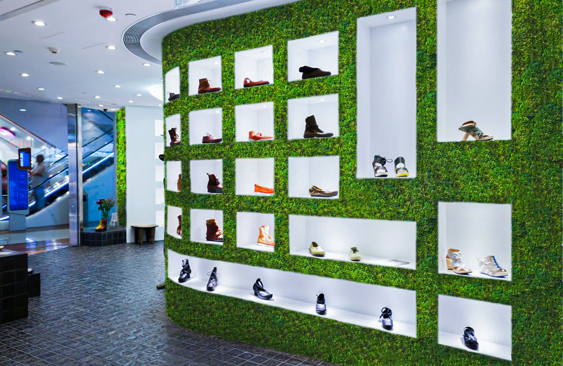 A stylish Edmonton retail space showcasing moss wall decor as a backdrop for an elegant shoe display.
