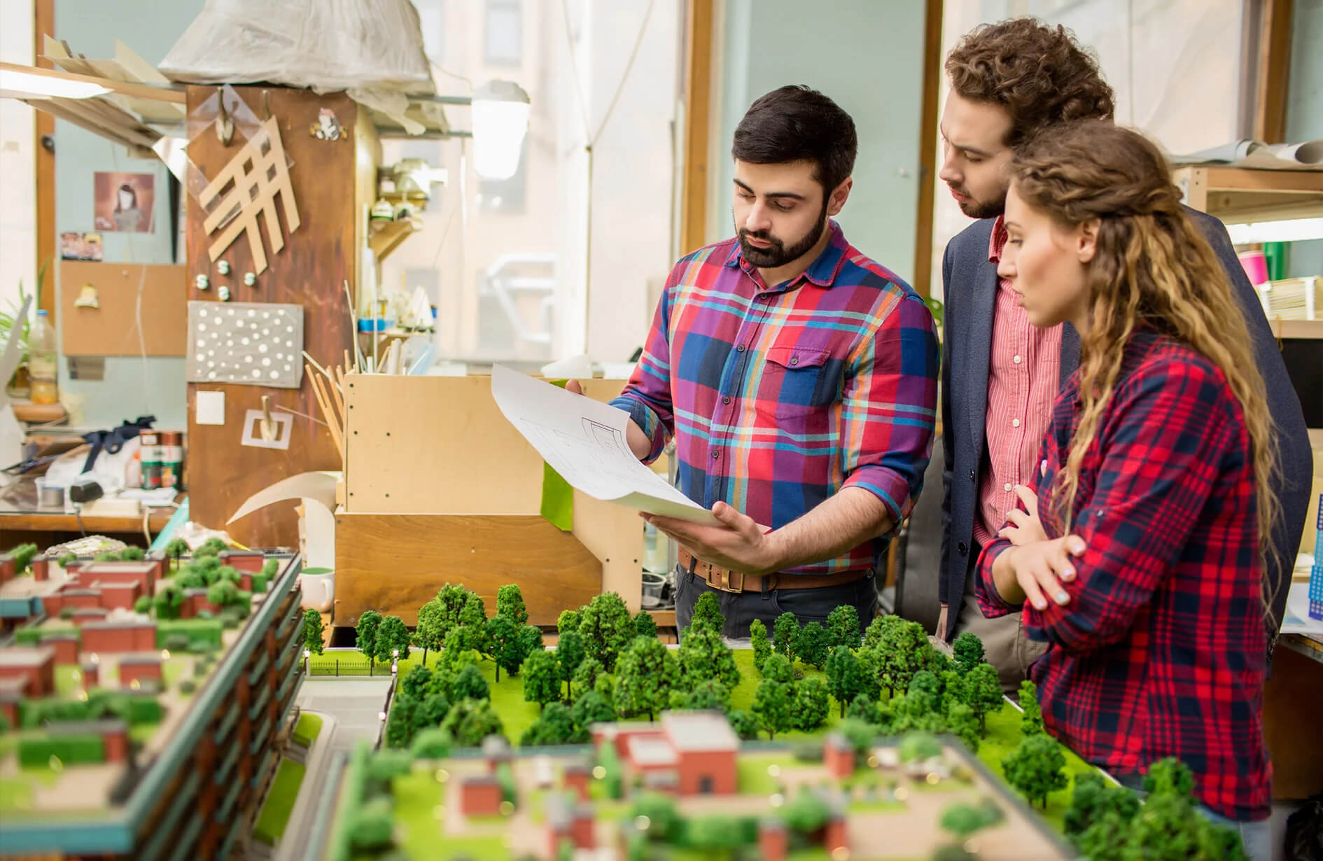 Landscape design company in Edmonton team reviewing plans over a detailed miniature model.