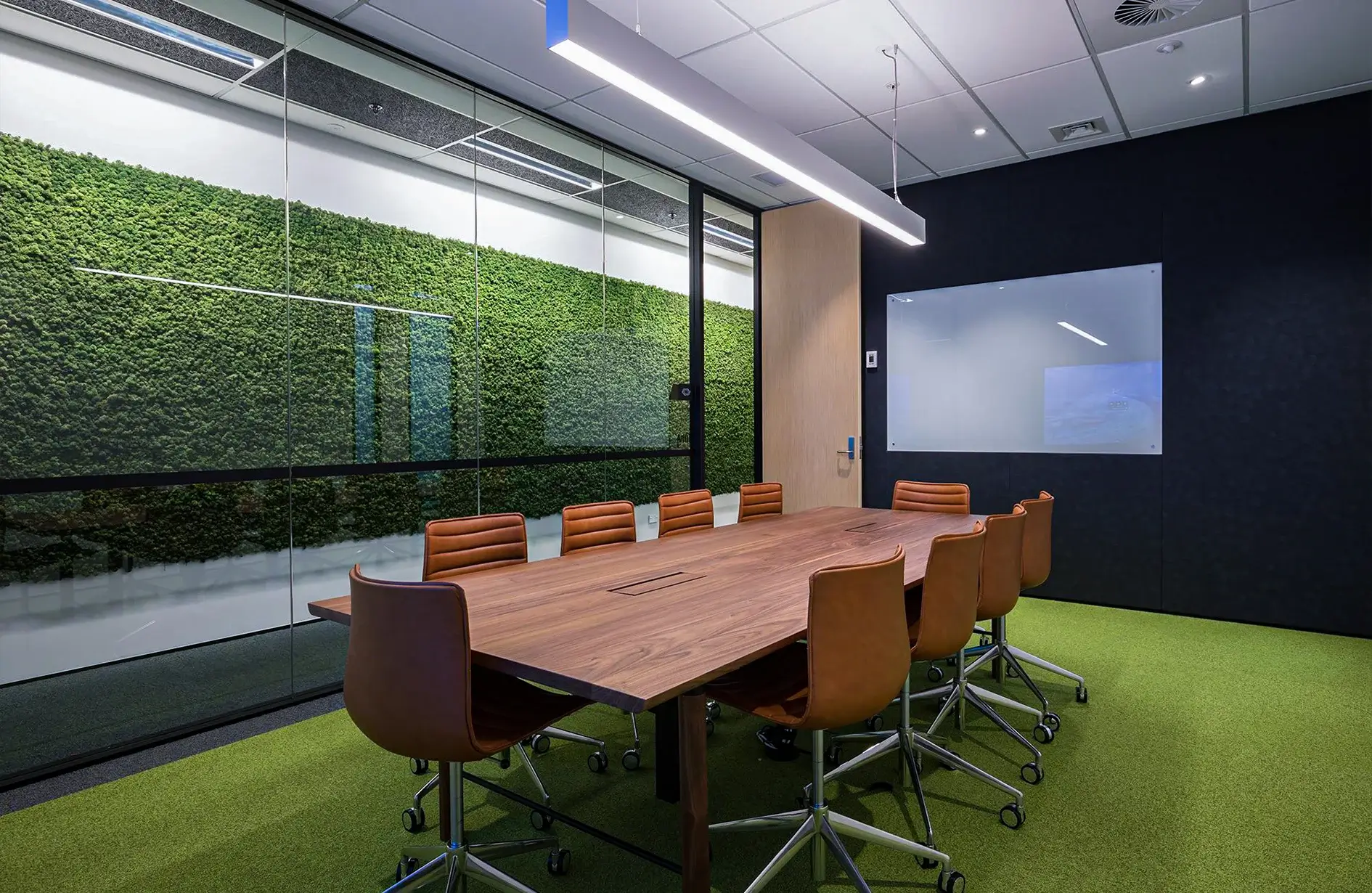 Modern Edmonton conference room with moss wall decor, wooden table, and leather chairs