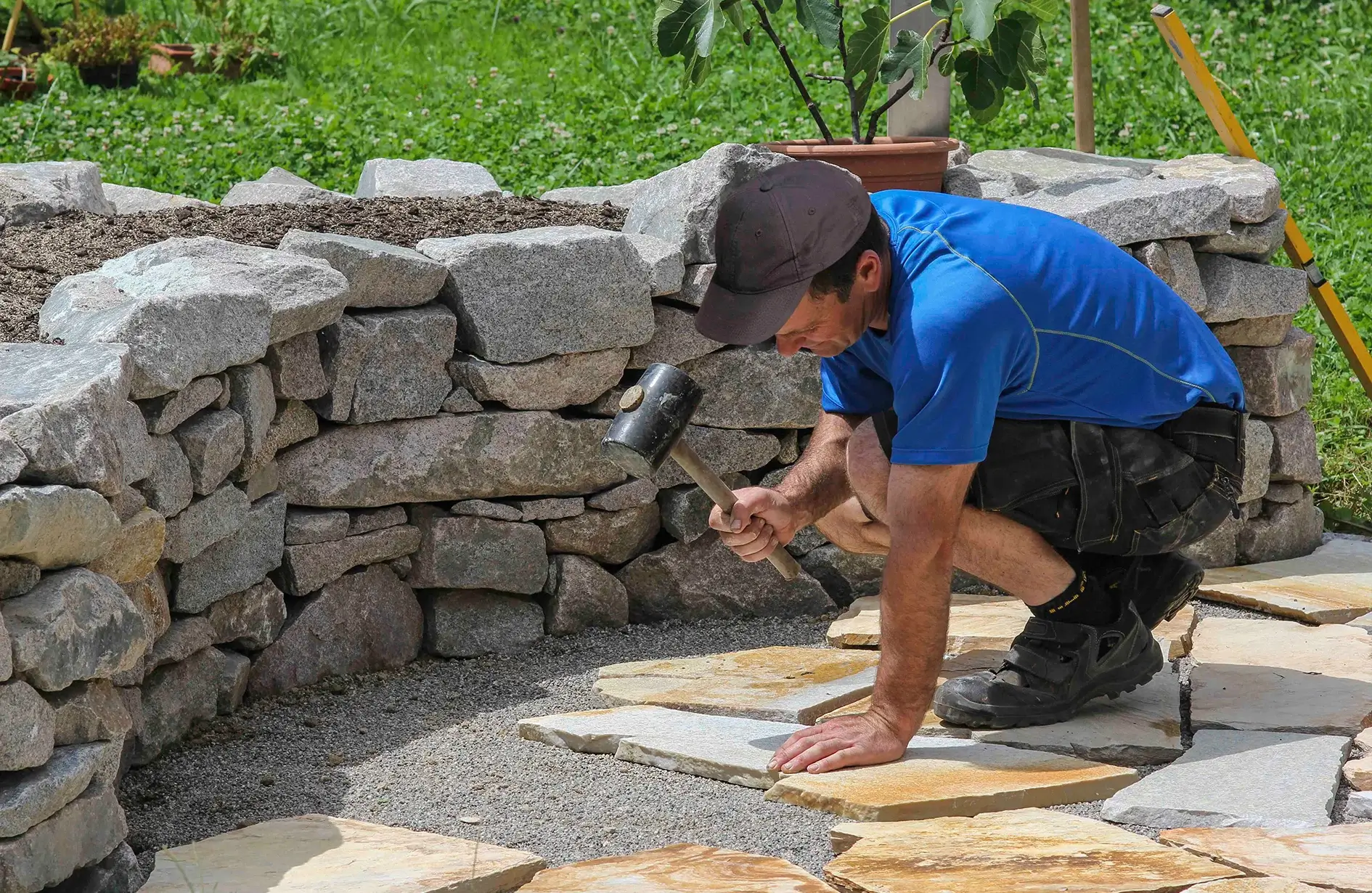 Man laying stone pavers for patio construction using trusted Edmonton landscaping materials.