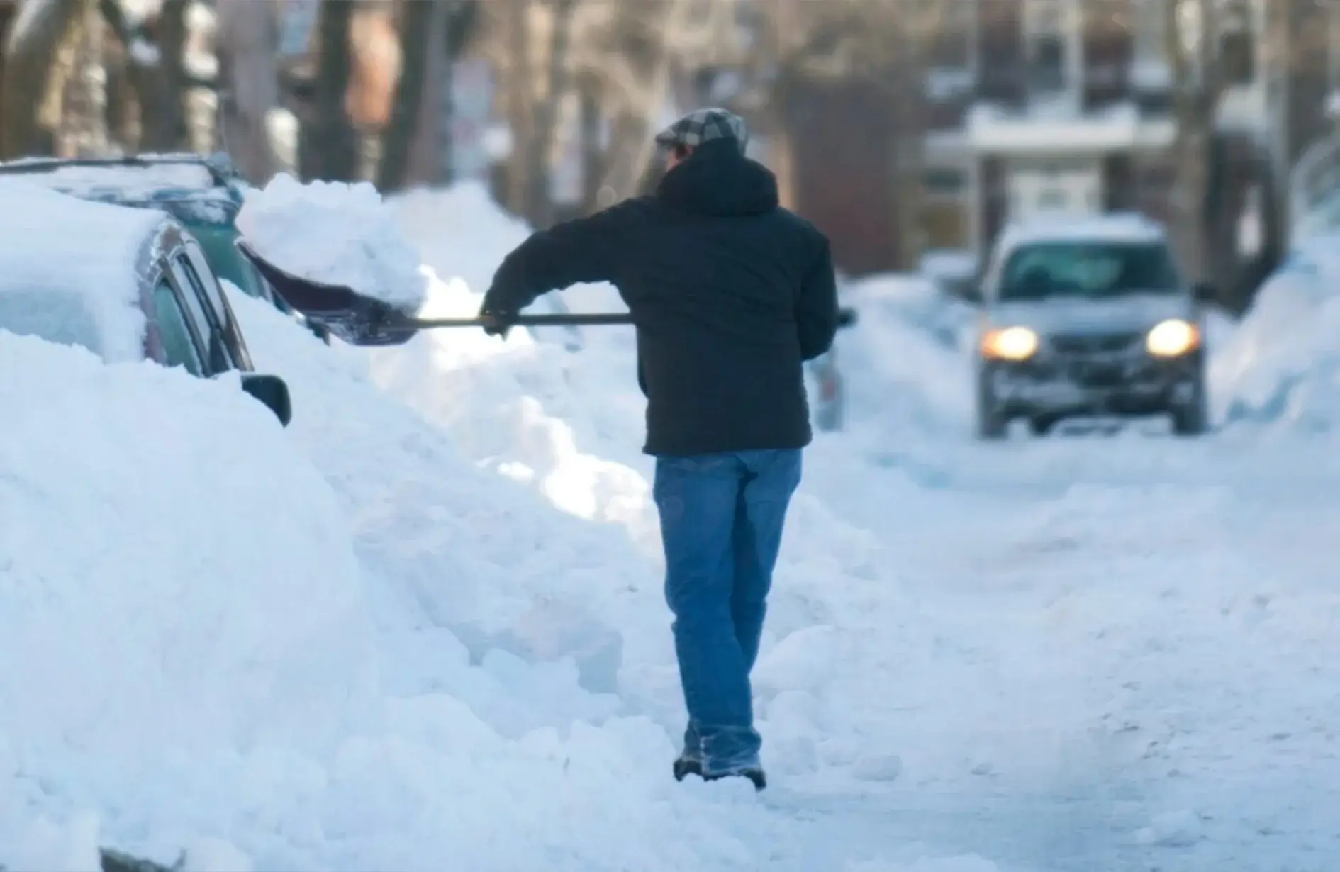 Person shoveling snow off car on snowy driveway
