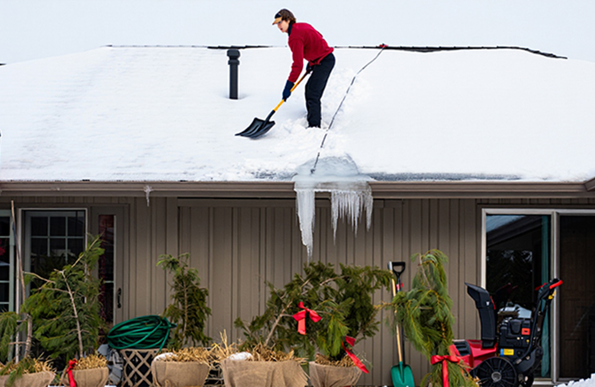Person shoveling snow off house roof in winter