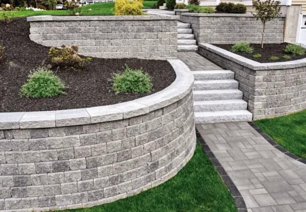Curved terraced stone retaining wall with steps and plants in Edmonton residential yard