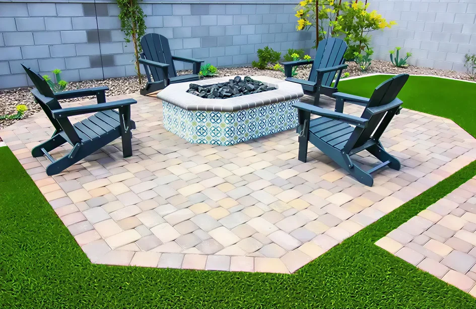 Custom residential patio design in Edmonton featuring interlock patio stones, a decorative tiled fire pit, and dark Adirondack chairs on a manicured lawn.